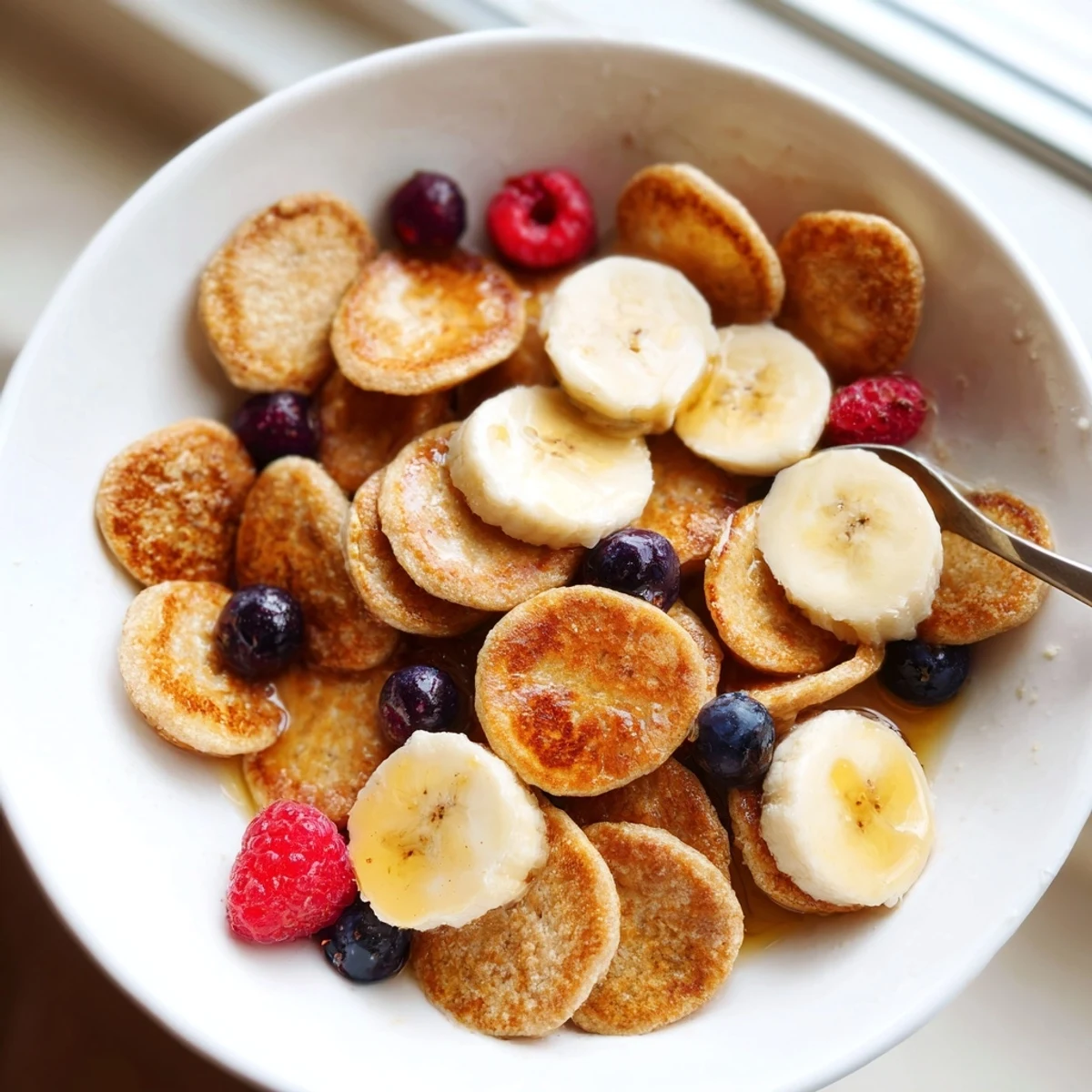 Delightful mini pancake cereal served with fresh berries and drizzled syrup.  