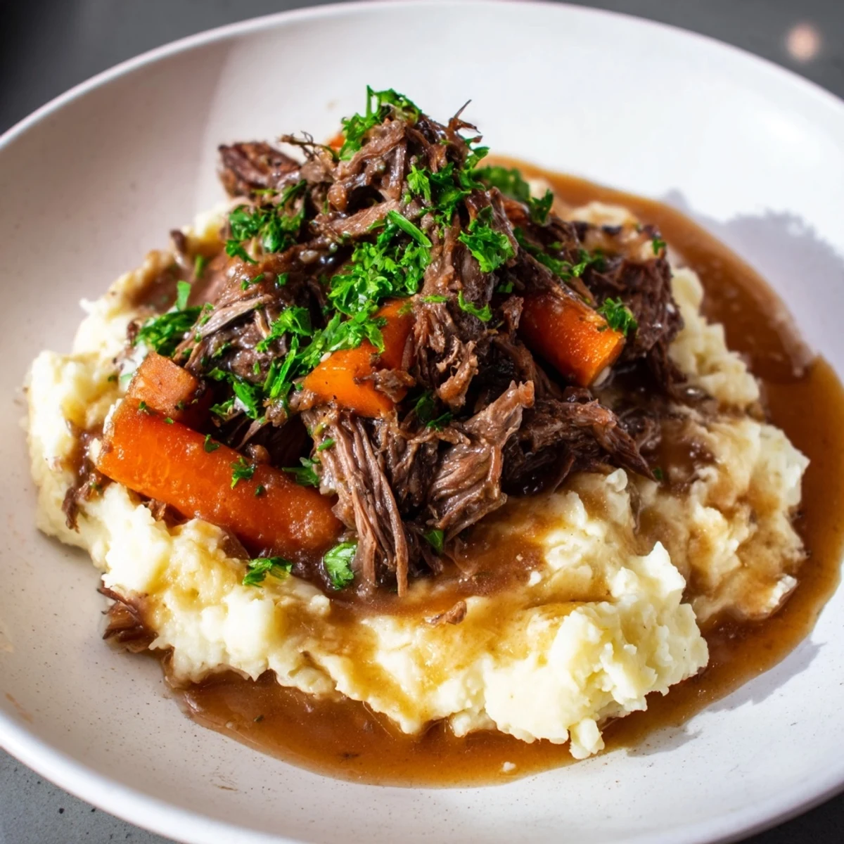 Tender slow cooker pot roast with vegetables and creamy mashed potatoes, ready to serve.