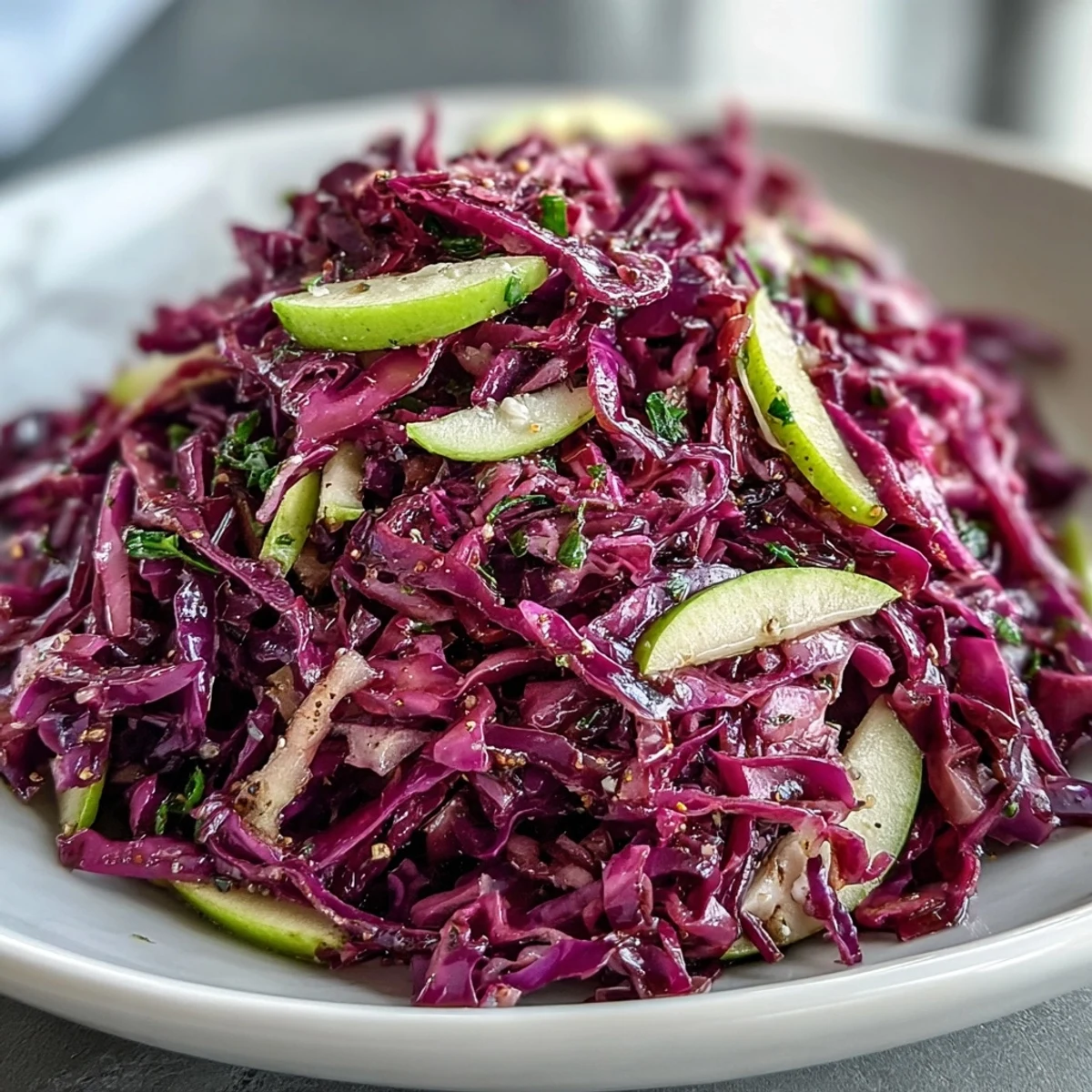 A vibrant bowl of Red Cabbage Coleslaw with Apple and Parmesan, tossed in a tangy vinaigrette.