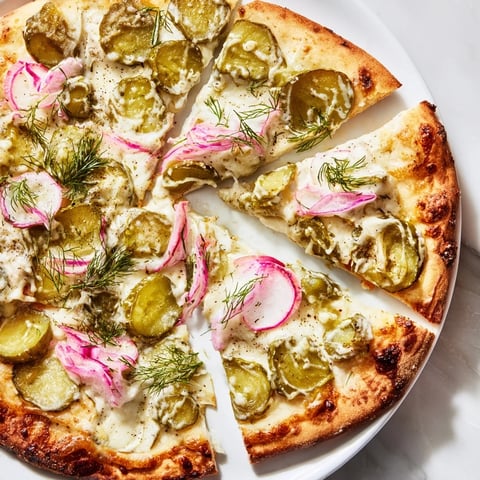 Tangy pickle pizza topped with creamy sauce, mozzarella, and crunchy dill slices.  