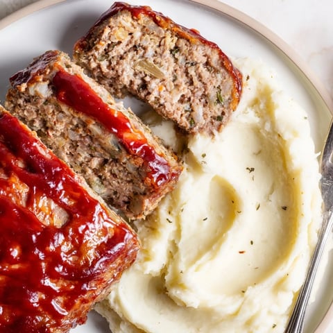 Classic meatloaf with rich ketchup glaze served alongside creamy mashed potatoes.  