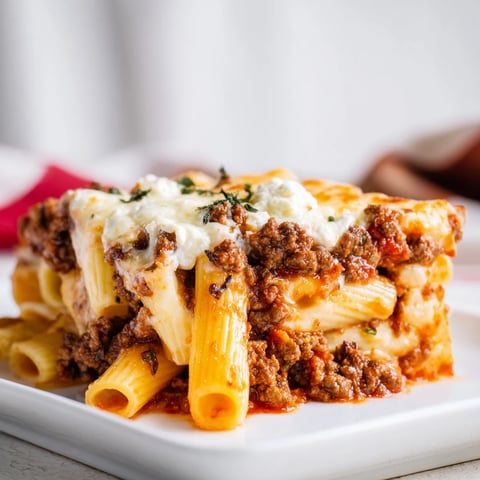 Steaming hot Baked Ziti with Meat Sauce, topped with bubbling mozzarella and a sprinkle of Parmesan cheese.