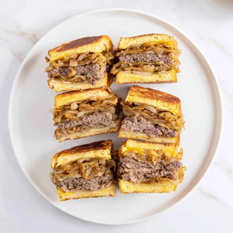 Juicy patty melt skillet with melted Swiss cheese, caramelized onions, and browned rye bread slices.