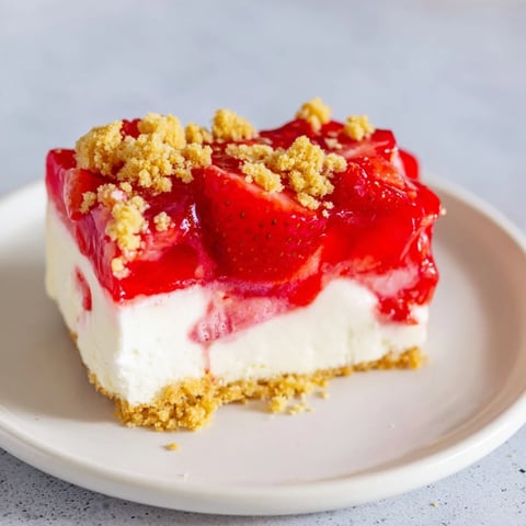 A slice of creamy strawberry shortcake cheesecake, showcasing its vibrant strawberry topping and crumble crust.