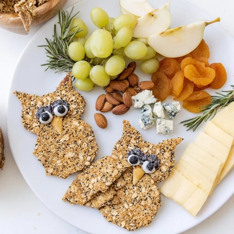 A colorful Owl Cracker and Cheese Board featuring a variety of cheeses and appealing snacks.