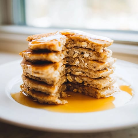 Perfect stack of golden-brown banana oat pancakes, ready to be topped with fresh berries.