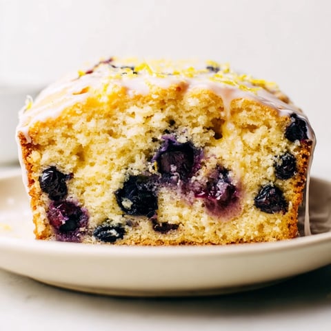 A slice of homemade Lemon Blueberry Yogurt Loaf, moist and bursting with fresh blueberries.