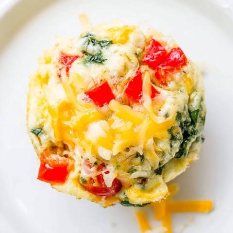 Golden-brown Customizable Egg Muffins, filled with colorful veggies and melted cheese, ready to eat.