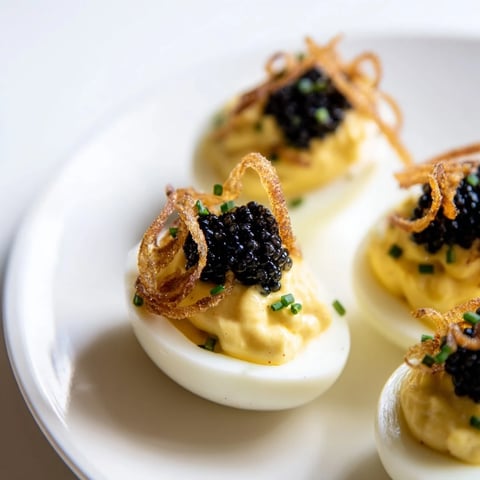 Elegant deviled eggs topped with caviar and crispy shallots, a gourmet appetizer idea.