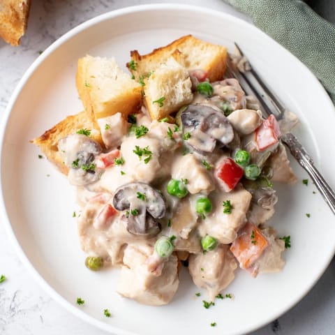Hearty chicken à la king with mushrooms and peas on toasted bread slices.  