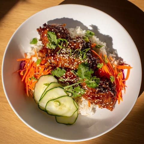 A steaming bowl of flavorful Sriracha Honey Chicken Rice, featuring tender chicken, fresh vegetables, and rice.