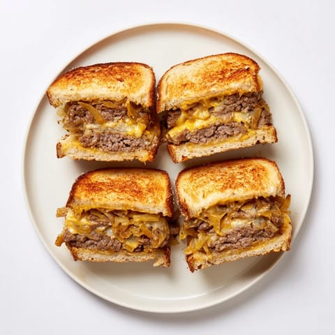 Close-up of a golden brown patty melt skillet, overflowing with cheese and perfectly cooked beef.