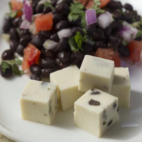 Close-up of a colorful platter of savory bites: Pepper Jack cubes and fresh black bean salsa.