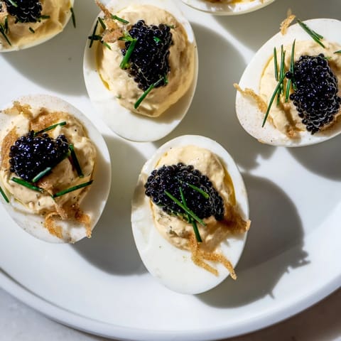 Creamy deviled eggs, showcasing luxurious caviar and golden crispy shallots, a party favorite.