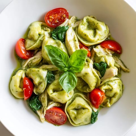 In this Creamy Pesto Tortellini Skillet, vibrant cherry tomatoes and fresh basil garnish a rich, cheesy main dish.  