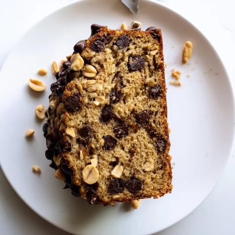 Perfectly sliced pieces of Chocolate Chip Peanut Butter Oatmeal Banana Bread reveal moist interior crumb, chunks of chocolate, and flecks of banana on a rustic wood surface.