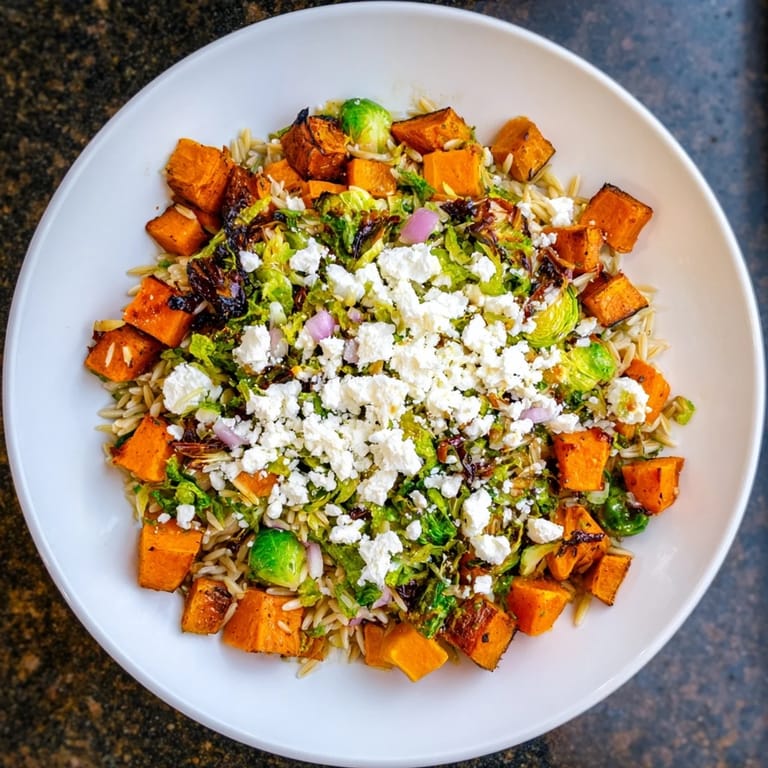 A close-up view of Best Fall Harvest Orzo Salad with glistening maple balsamic dressing and soft cheese.