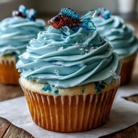 Whimsical vanilla cupcakes topped with fondant fish and blue buttercream, perfect for Pisces birthdays and zodiac celebrations.
